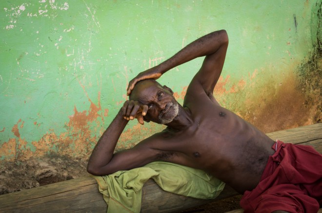 An old man rests in front of a colourful wall in Kwesikrum, Ghana.